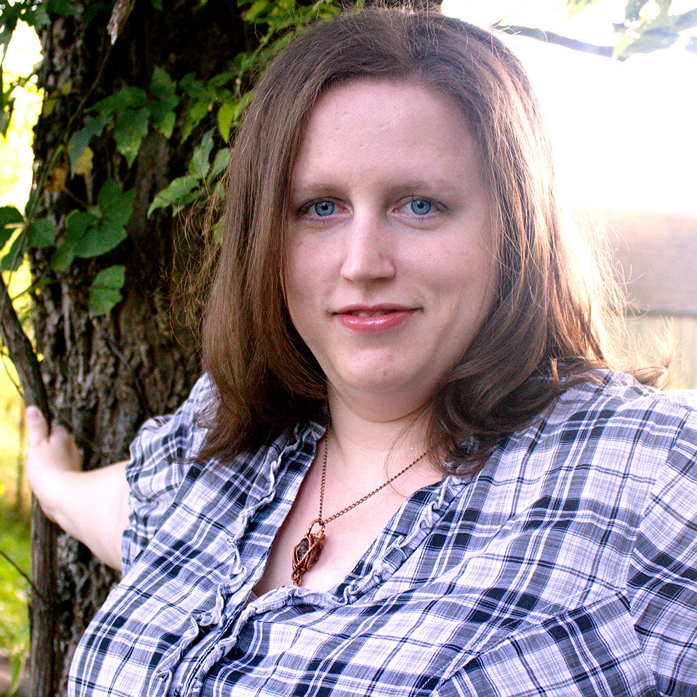 A picture of author Bethany Adams standing in front of a tree. She has dark blonde hair and blue eyes.